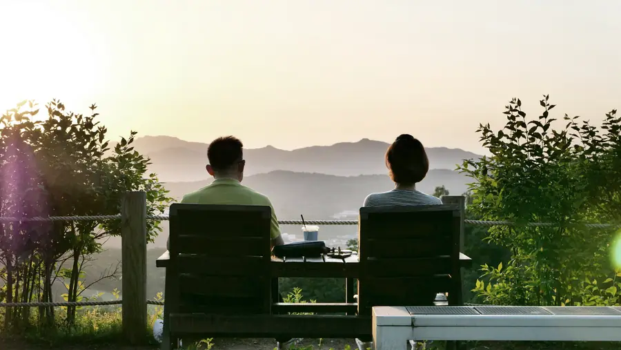A couple enjoying the view of green hills at sunset